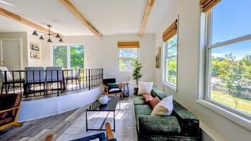 A spacious living room with a large window, a sofa, a coffee table, and a fireplace.