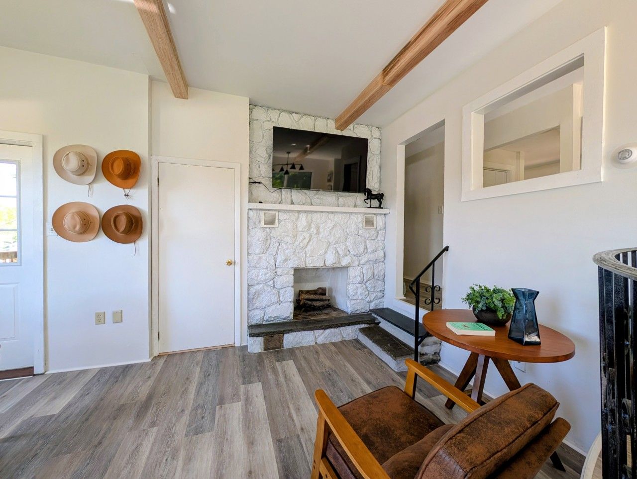 A room with a stone fireplace, wooden flooring, and a dining area with a table and chairs.