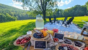 Een picknickopstelling buiten met verschillende soorten eten en een bordje met de tekst 'Geniet ervan!'