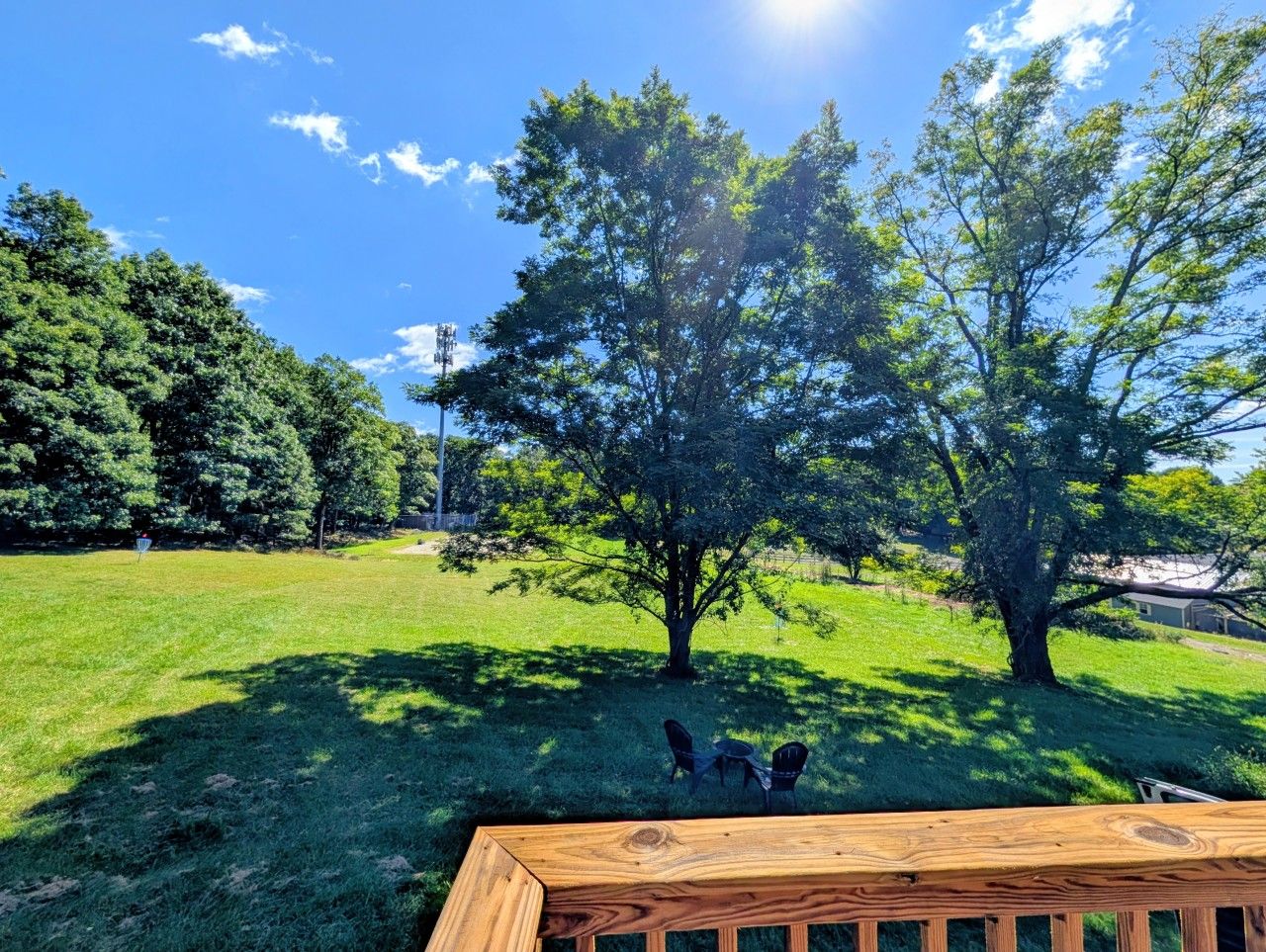A grassy outdoor area with a wooden deck and two chairs.