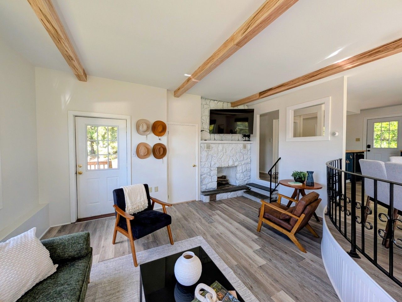 A spacious living area with a fireplace, wooden beams, and a view of the outdoors.
