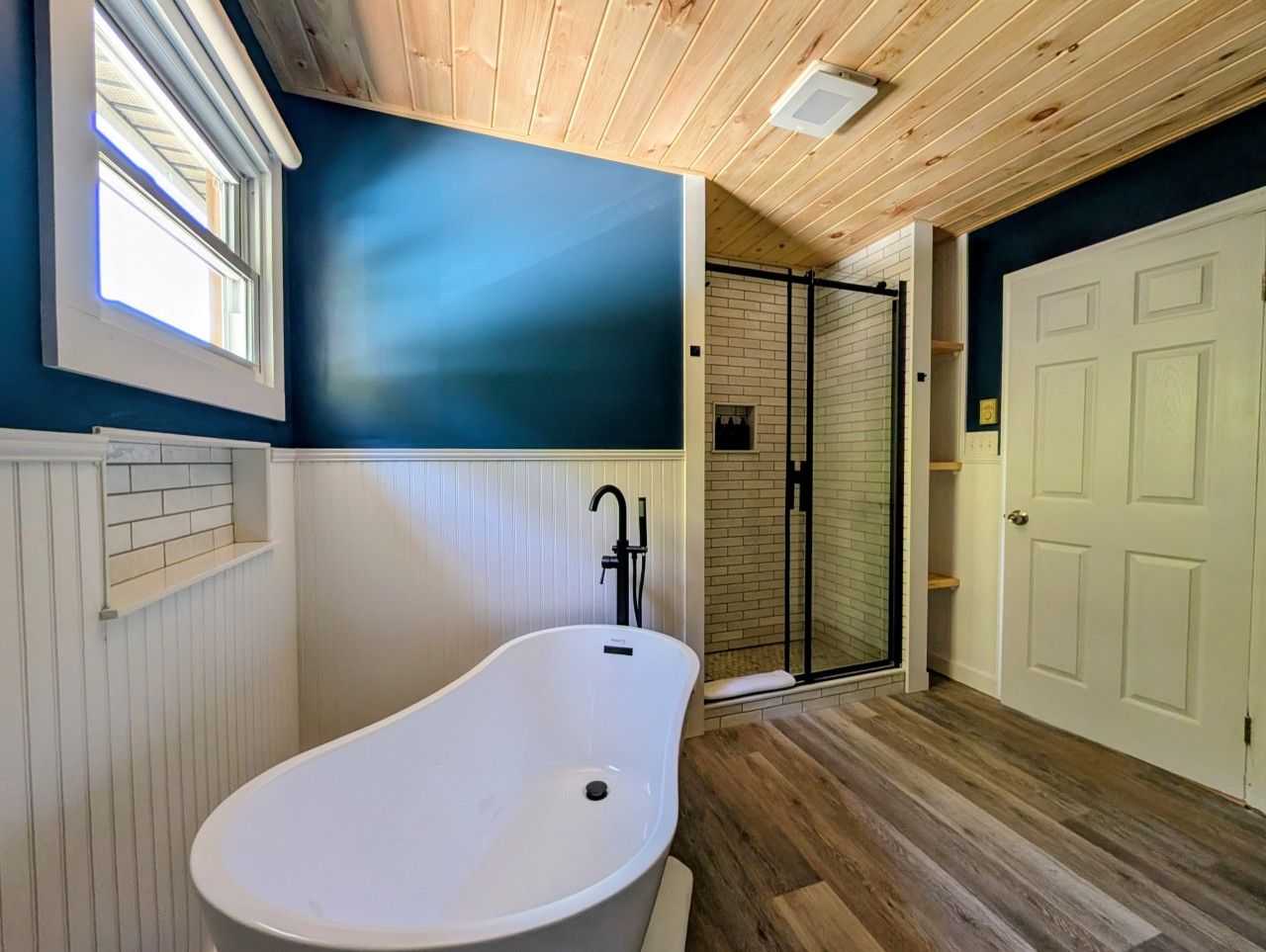 Une salle de bain avec une baignoire sur pieds, un espace douche et une porte.