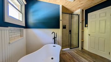 Une salle de bain avec une baignoire sur pieds, un espace douche et une porte.