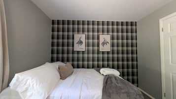 A bedroom with a bed, a pillow, a blanket, and a door.