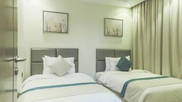 Une chambre d’hôtel avec deux lits, chacun doté d’une tête de lit, de draps blancs et d’un élément décoratif de couleur turquoise.