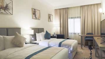 A hotel room with two beds, a desk, a chair, and a television.