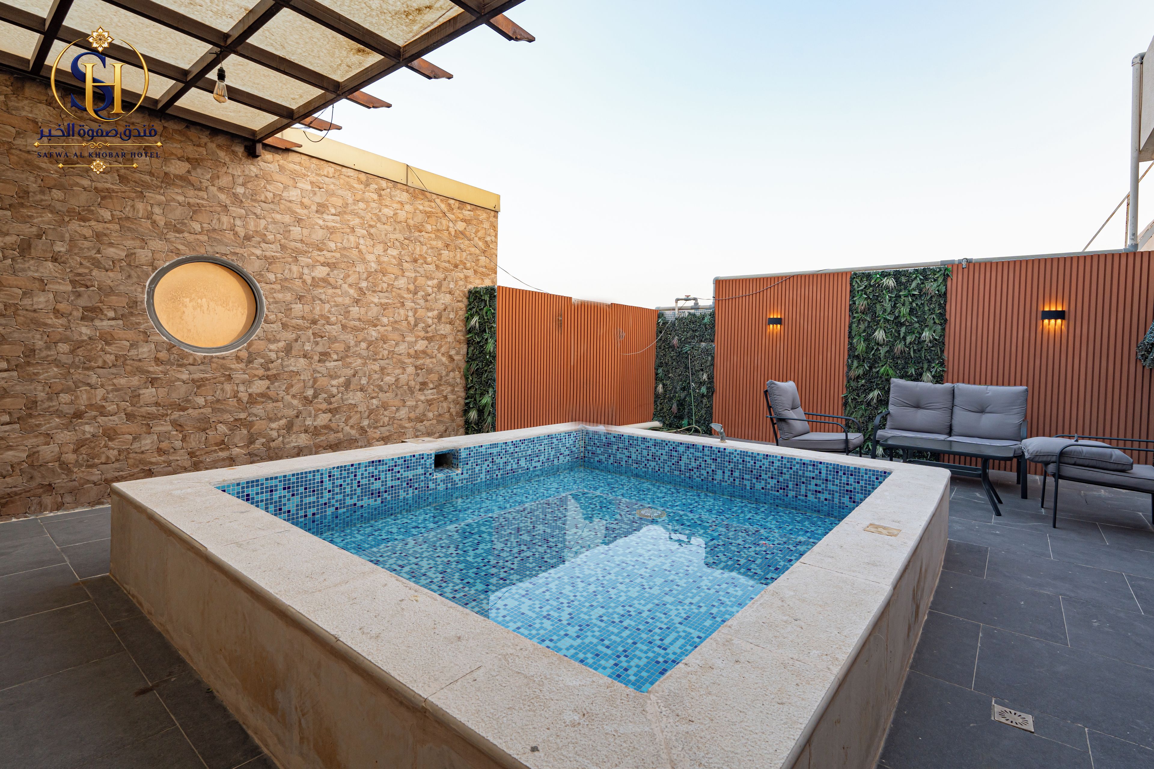 Una piscina con una pared de piedra y una valla de madera al fondo.
