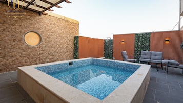 Una piscina con una pared de piedra y una valla de madera al fondo.