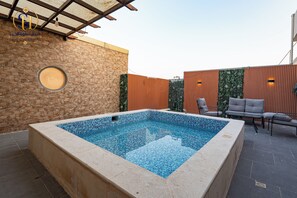 Una piscina con una pared de piedra y una valla de madera al fondo.