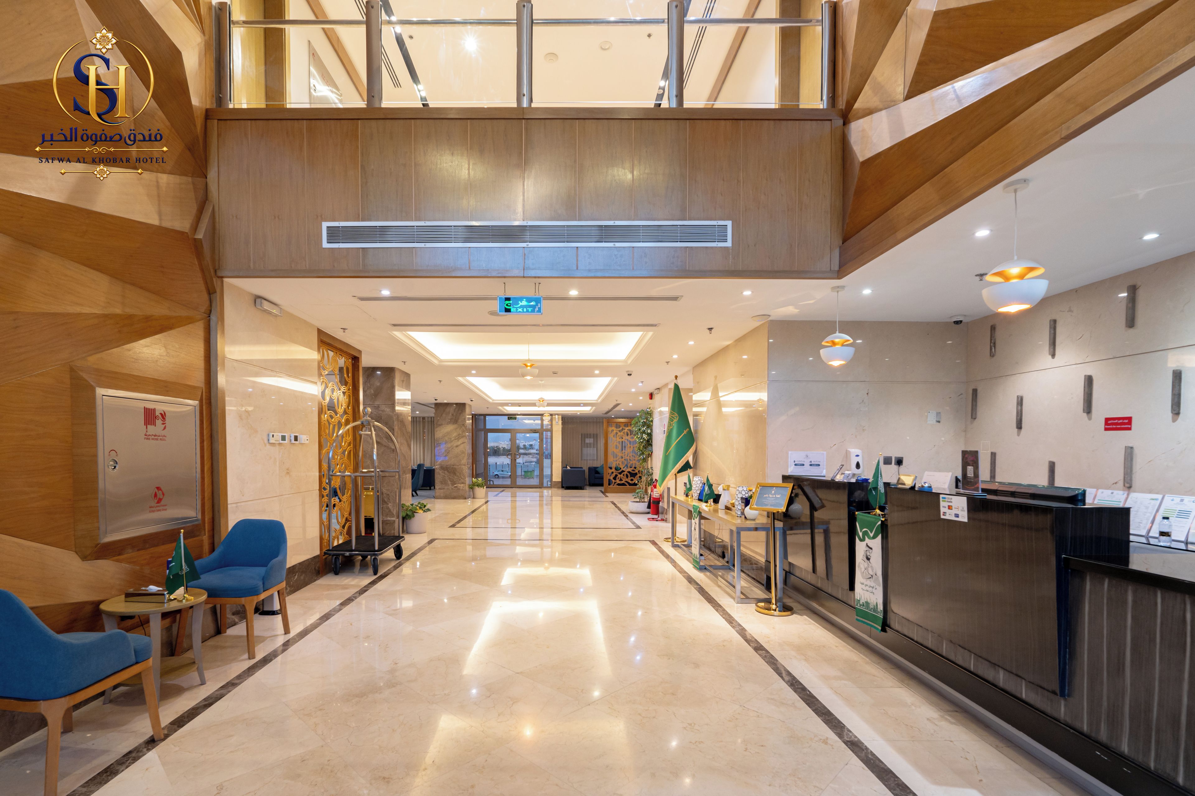 A hotel lobby with a reception desk, seating area, and a view of the entrance.