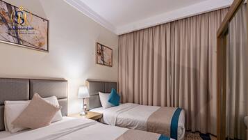 Una habitación de hotel con dos camas, una mesita de noche, una lámpara y un ventanal grande con cortinas.