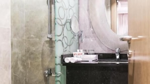 Ein Badezimmer mit Duschkabine aus Glas, einem schwarzen Waschtisch und einem großen Spiegel.