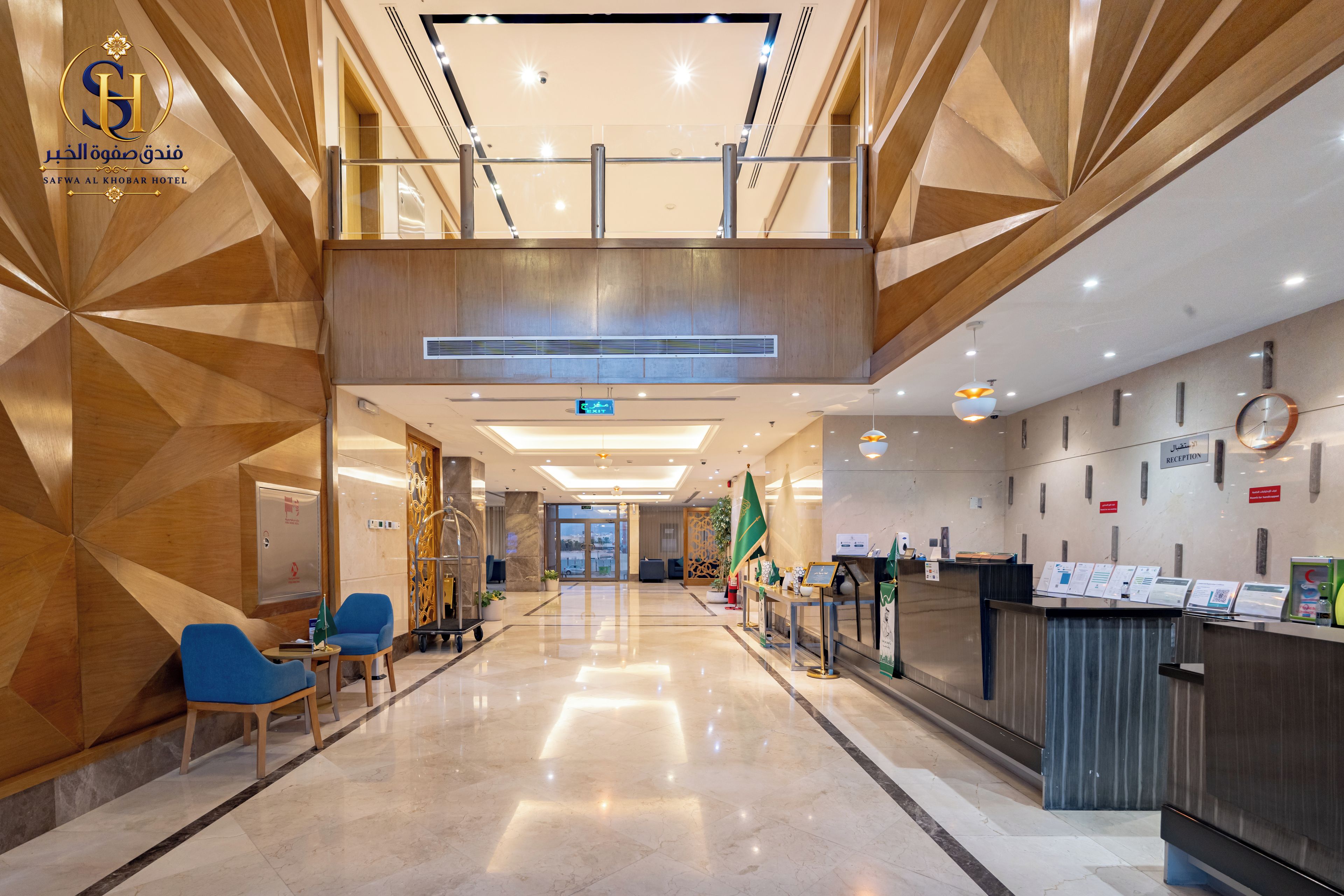 Vestíbulo de hotel con recepción, zona de estar y vistas al estacionamiento.