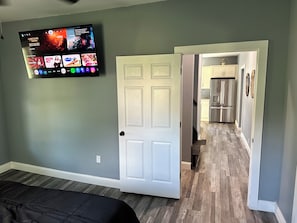 A room with a bed, a TV mounted on the wall, and a door leading to a kitchen area. - Newly Renovated House in Buffalo, Ky (Buffalo)