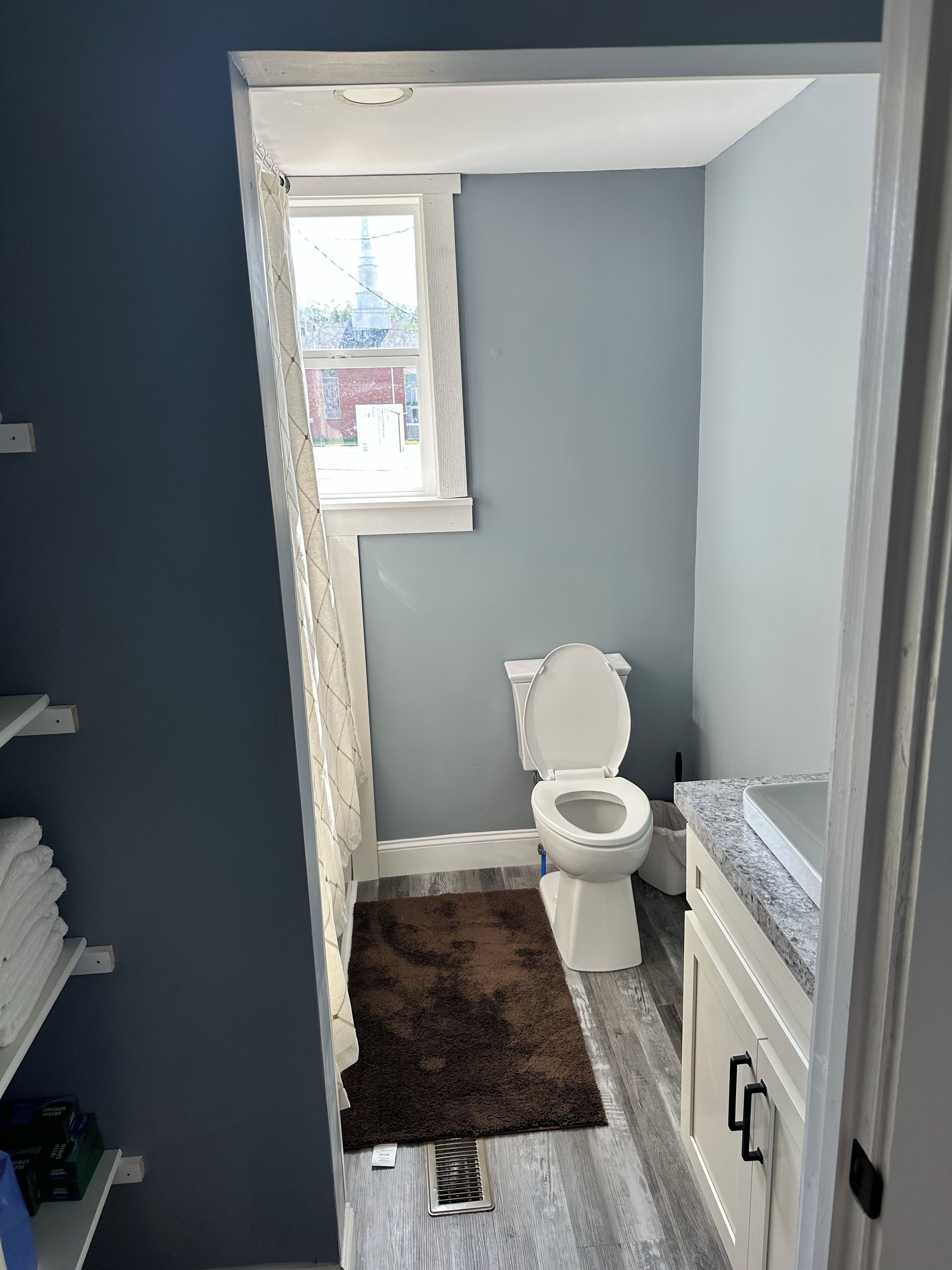 Une salle de bain comprenant des toilettes, un espace douche et une fenêtre.