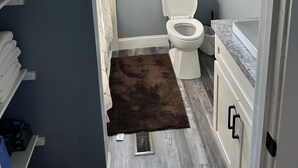 A bathroom with a toilet, a shower area, and a window. - Newly Renovated House in Buffalo, Ky (Buffalo)