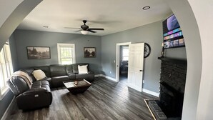 A living room with a sectional sofa, a coffee table, a fireplace, and a television mounted on the wall. - Newly Renovated House in Buffalo, Ky (Buffalo)