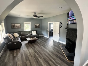 A living room with a sectional sofa, a coffee table, a fireplace, and a television mounted on the wall. - Newly Renovated House in Buffalo, Ky (Buffalo)