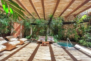 Espaço de descanso ao ar livre com espreguiçadeiras, piscina e vegetação exuberante.
