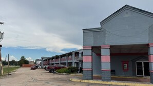 A multi-story building with a covered entrance and a parking lot in front. - Blue Way Inn & Suites Houston - Katy/Rosenberg Standard 1 King Bed NS (Rosenberg)