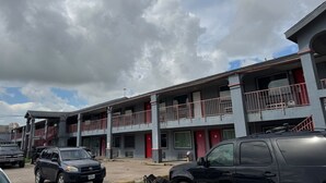 A multi-story motel with balconies, a parking lot, and a clear sky. - Blue Way Inn & Suites Houston - Katy/Rosenberg Standard 1 King Bed NS (Rosenberg)