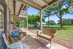 A covered outdoor seating area with wicker furniture and a view of a grassy park. - Seascape Villa 2A *Updated*Quiet villa*Beach access* (Miramar Beach)
