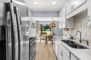 A modern kitchen with stainless steel appliances, a large island with seating, and a view to the outdoors. - The Sandpiper Pearl - Seascape Villa 2A *Updated*Quiet villa*Beach access* (Miramar Beach)