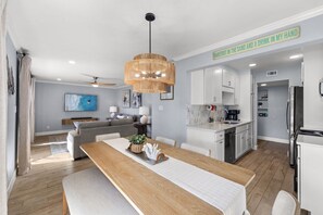 Een moderne keuken met witte kasten, een roestvrijstalen koelkast en een eethoek met een houten tafel en stoelen.