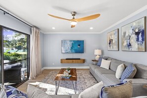Un salon moderne avec un ventilateur de plafond, un téléviseur à écran plat, un canapé et une table basse.