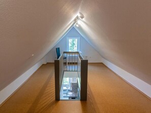 Une chambre mansardée avec un plafond en pente, une fenêtre et une vue sur l’extérieur.