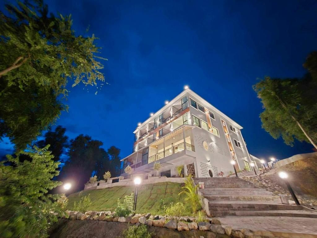 Un immeuble à plusieurs étages doté d’une architecture moderne, avec un balcon imposant situé au dernier niveau.