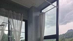Ein Badezimmer mit freistehender Badewanne, einer Dusche und Blick auf einen Fluss und Wald durch große Fenster.