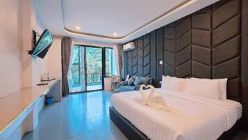 A modern hotel room with a large bed, a flat-screen TV mounted on the wall, and a balcony with a view of the outdoors.