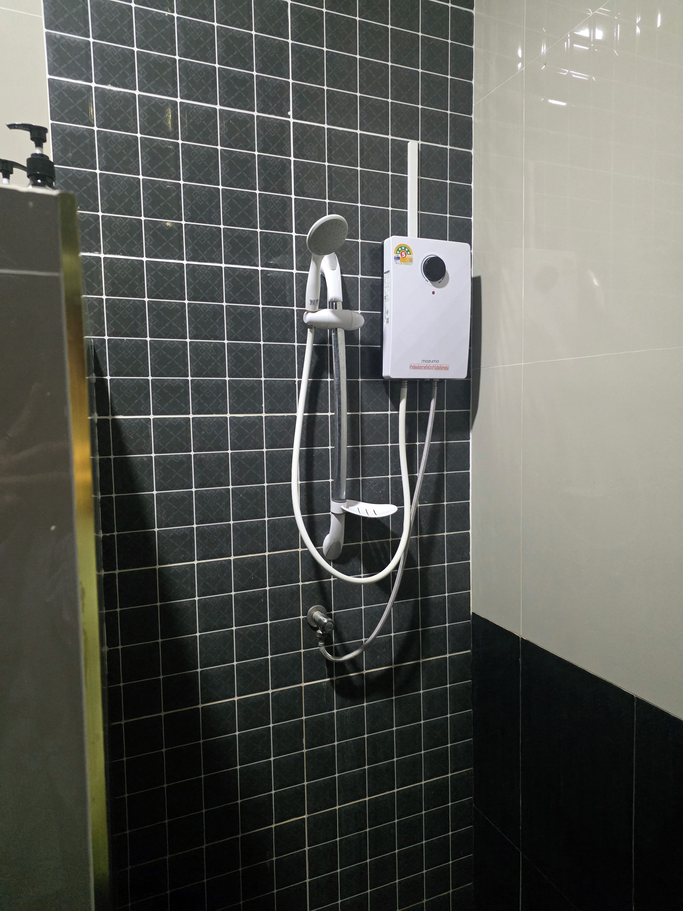 Zona de ducha con un gabinete empotrado en la pared, un cabezal de ducha manual y una manguera de ducha.