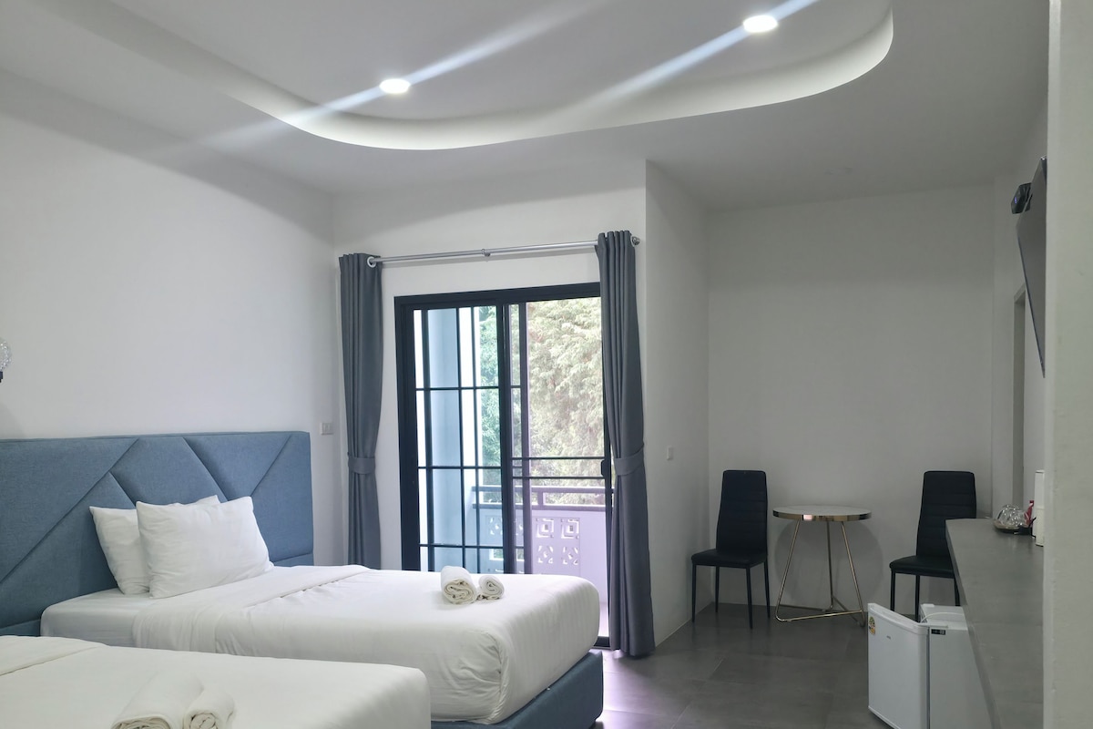 Hotellihuone, jossa on kaksi sänkyä, työpöytä ja tuoli.