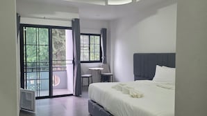 Ein modernes Hotelzimmer mit einem großen Bett, einem Schreibtisch und Blick durch eine Glastür.