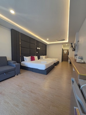 Moderni hotellihuone, jossa on sänky, sohva, työpöytä ja kylpyhuone.