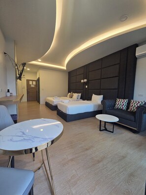 A modern hotel room with a curved ceiling, a sofa, a bed with two pillows, a small round table, and a chair. - KIREERIVER (Thong Pha Phum)