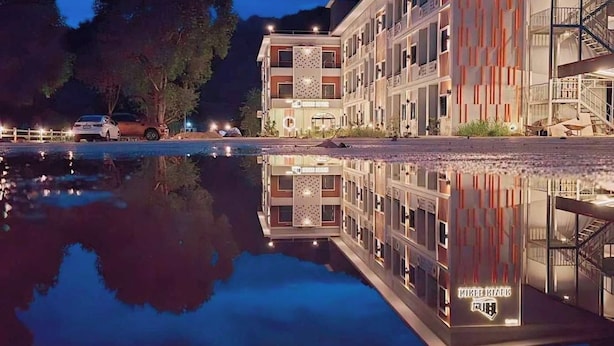 Ein mehrstöckiges Hotel mit einem spiegelnden Pool davor.