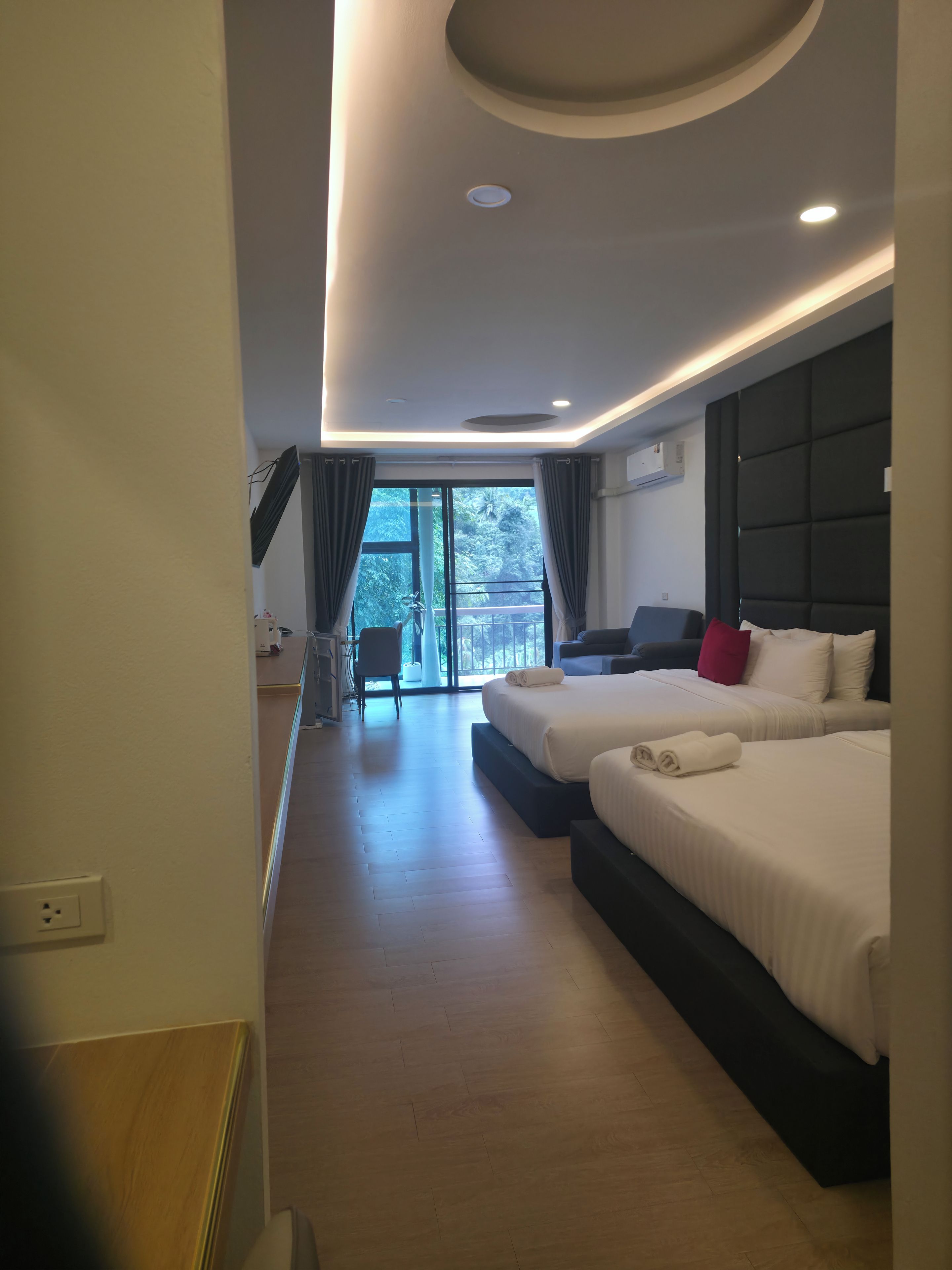 Habitación de hotel moderna con dos camas, zona de estar y vistas al exterior.
