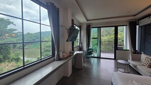 Una habitación de hotel con un ventanal grande, un televisor de pantalla plana, un sofá y una cama.
