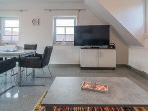 A modern living room with a flat-screen TV, a dining area with a table and chairs, and a small decorative tray on the floor. - Holiday Apartment With 2 Bedrooms (Esens)