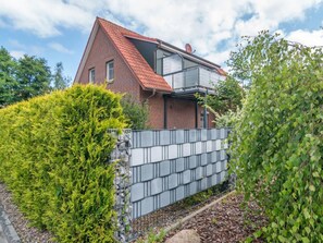 A two-story house with a red-tiled roof, a satellite dish, and a metal fence. - Holiday Apartment With 2 Bedrooms (Esens)