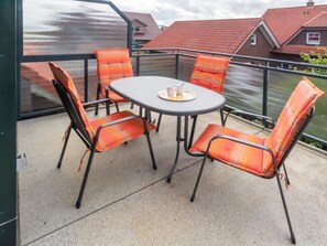 A balcony with a table and chairs, a view of houses, and a railing. - Holiday Apartment With 2 Bedrooms (Esens)