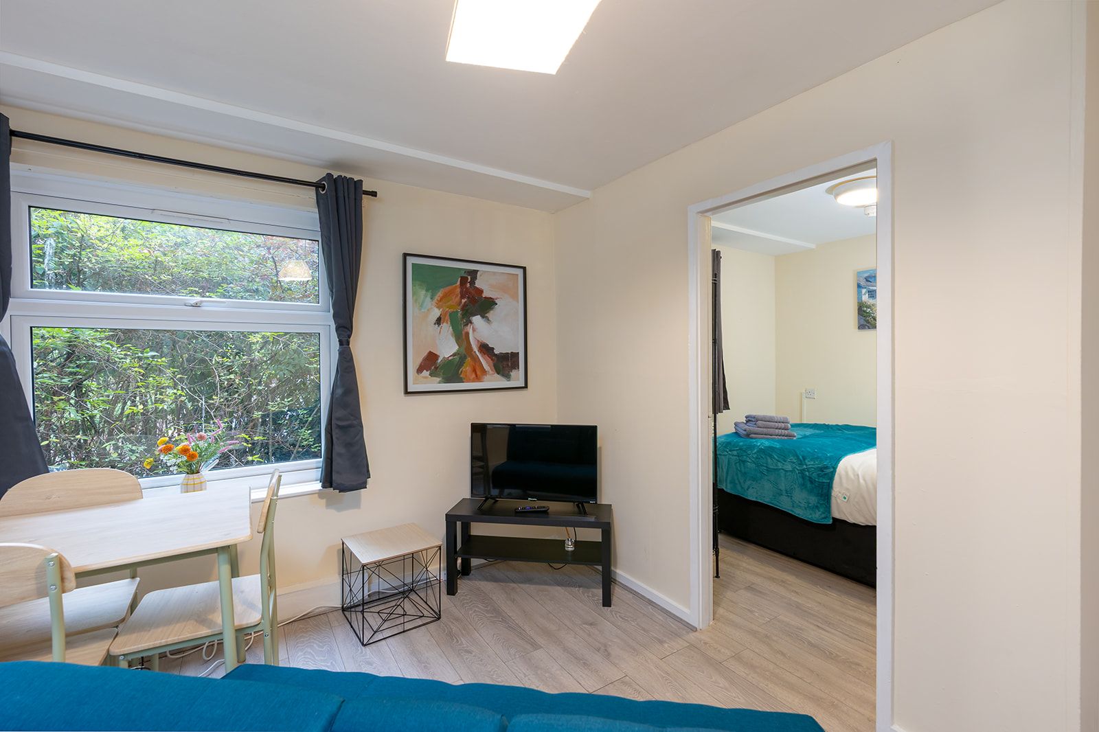 A room with a bed, a desk, a television, and a window with curtains.