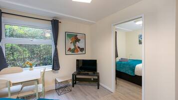 A room with a bed, a desk, a television, and a window with curtains.