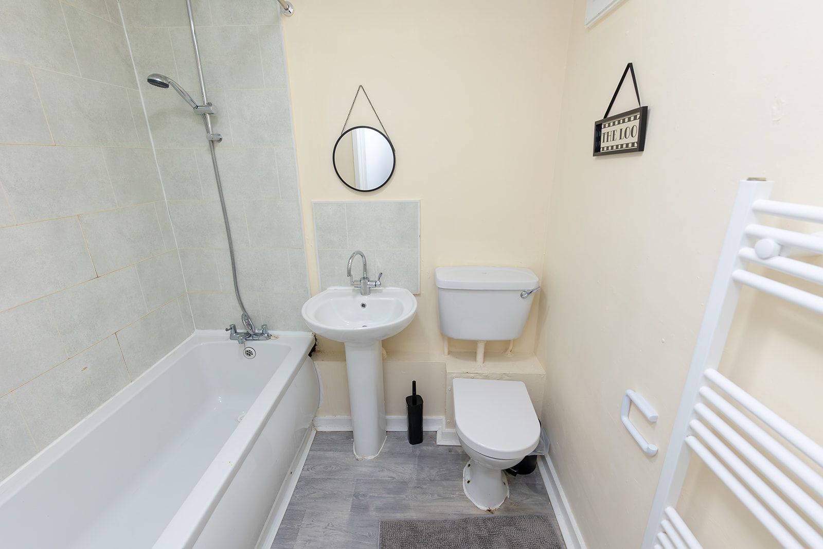 A compact bathroom with a bathtub, sink, toilet, and a shower.