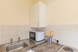 A kitchen with a stainless steel sink, a microwave, and a white cabinet above the counter. - 1BR Flat w/ King sized beds | Near Station (Stockton-on-Tees)