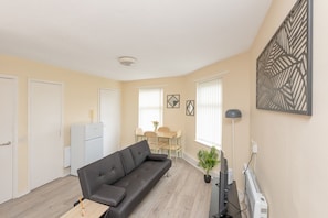 A compact living space with a sofa, dining table, and a small kitchenette. - 1BR Flat w/ King sized beds | Near Station (Stockton-on-Tees)