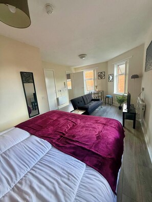 A bedroom with a large bed, a sofa, a small table, and a potted plant. - 1BR Flat w/ King sized beds | Near Station (Stockton-on-Tees)